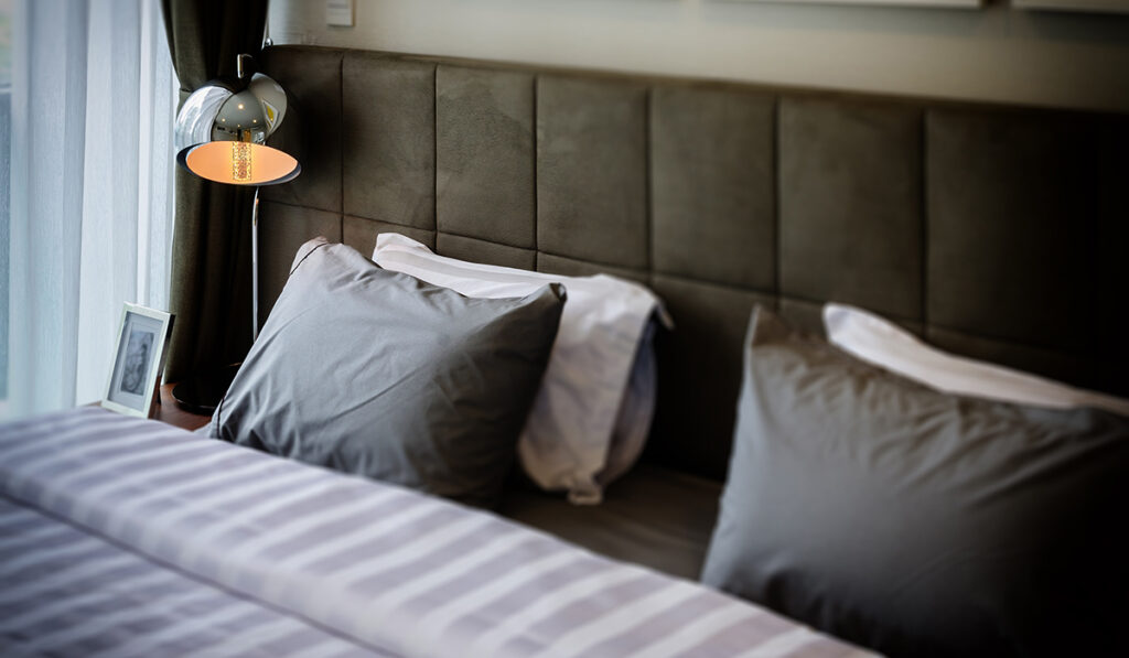 grey pillows on bed with modern lamp at home