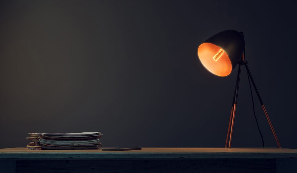 Office desk with lamp, mobile phone and paperwork stack